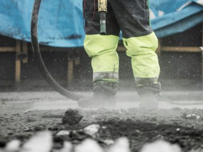Construction worker operating heavy machinery at a building site, ensuring safety and precision.